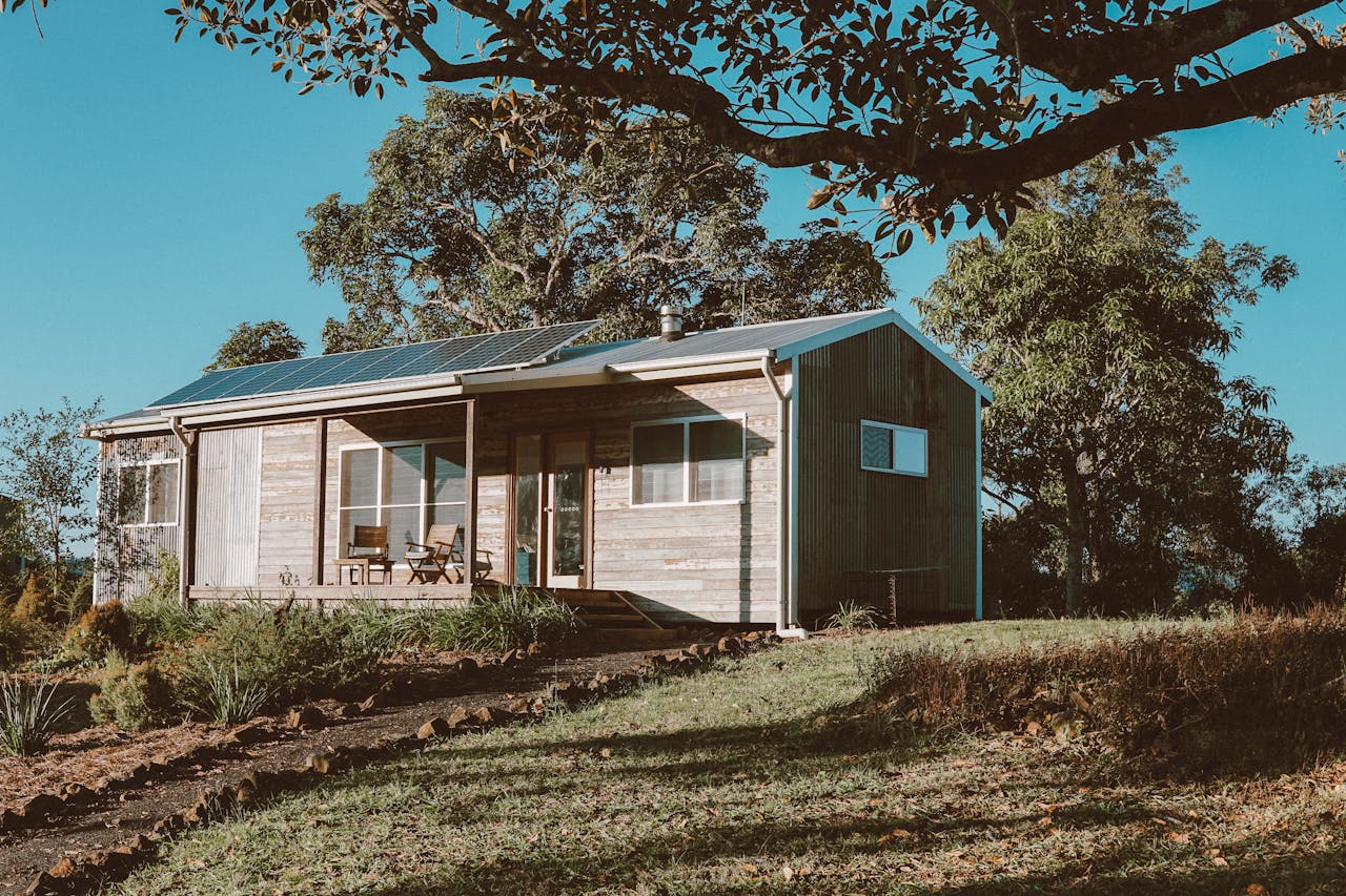 wooden house with solar panels near green trees