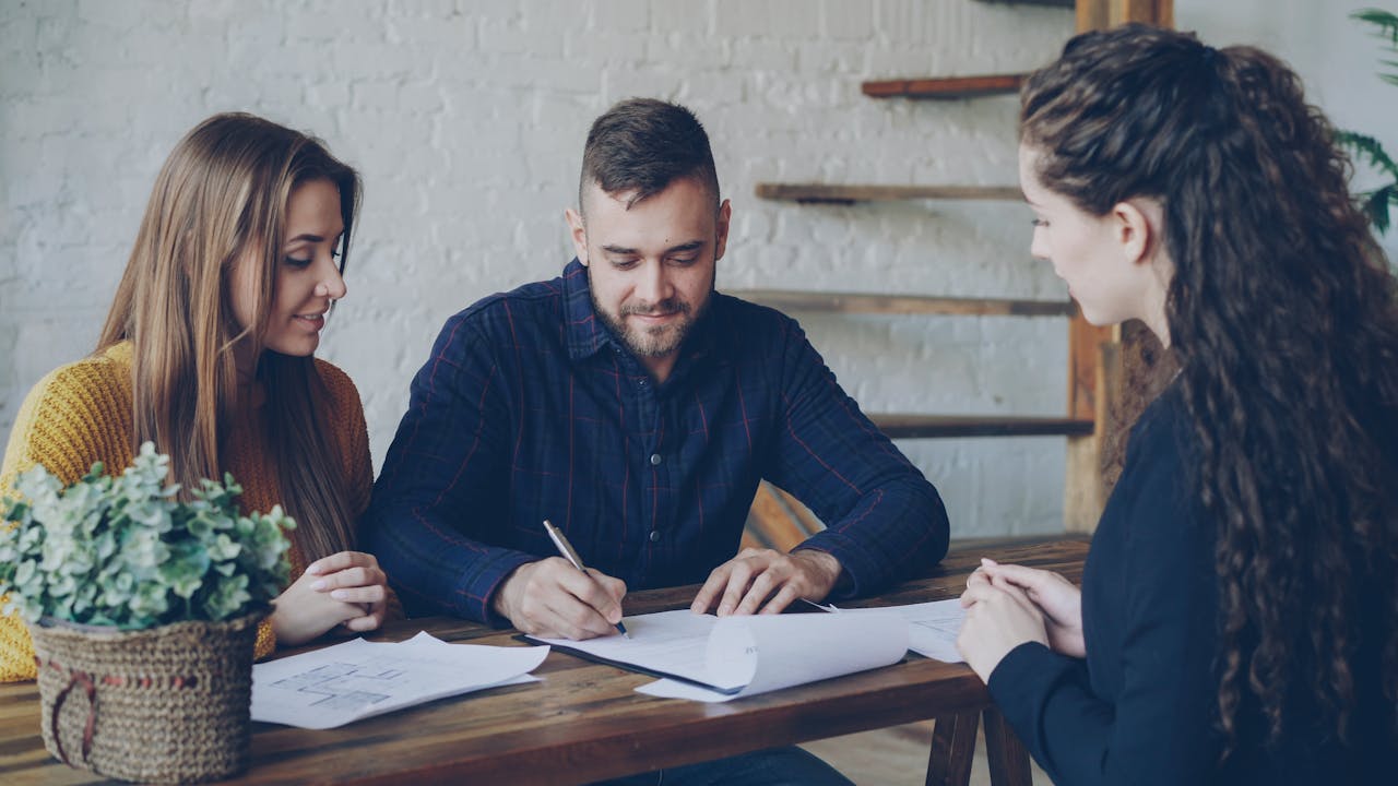 Real estate agent and homebuyer reviewing a builder contract at a desk
