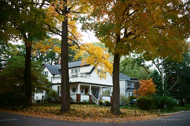 charming white house surrounded by autumn trees